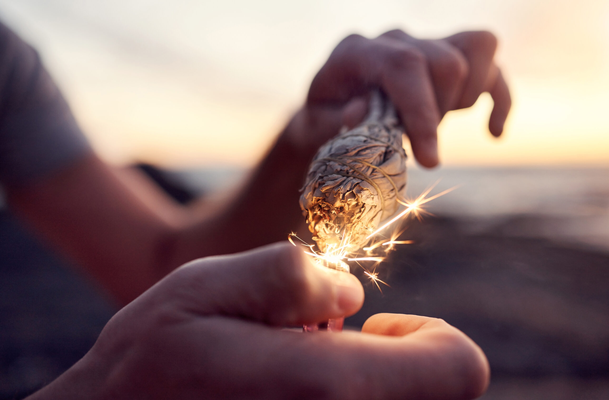 Hand, flame and sage burning at the beach for a spiritual ritual and meditation practice. Herb, fin.